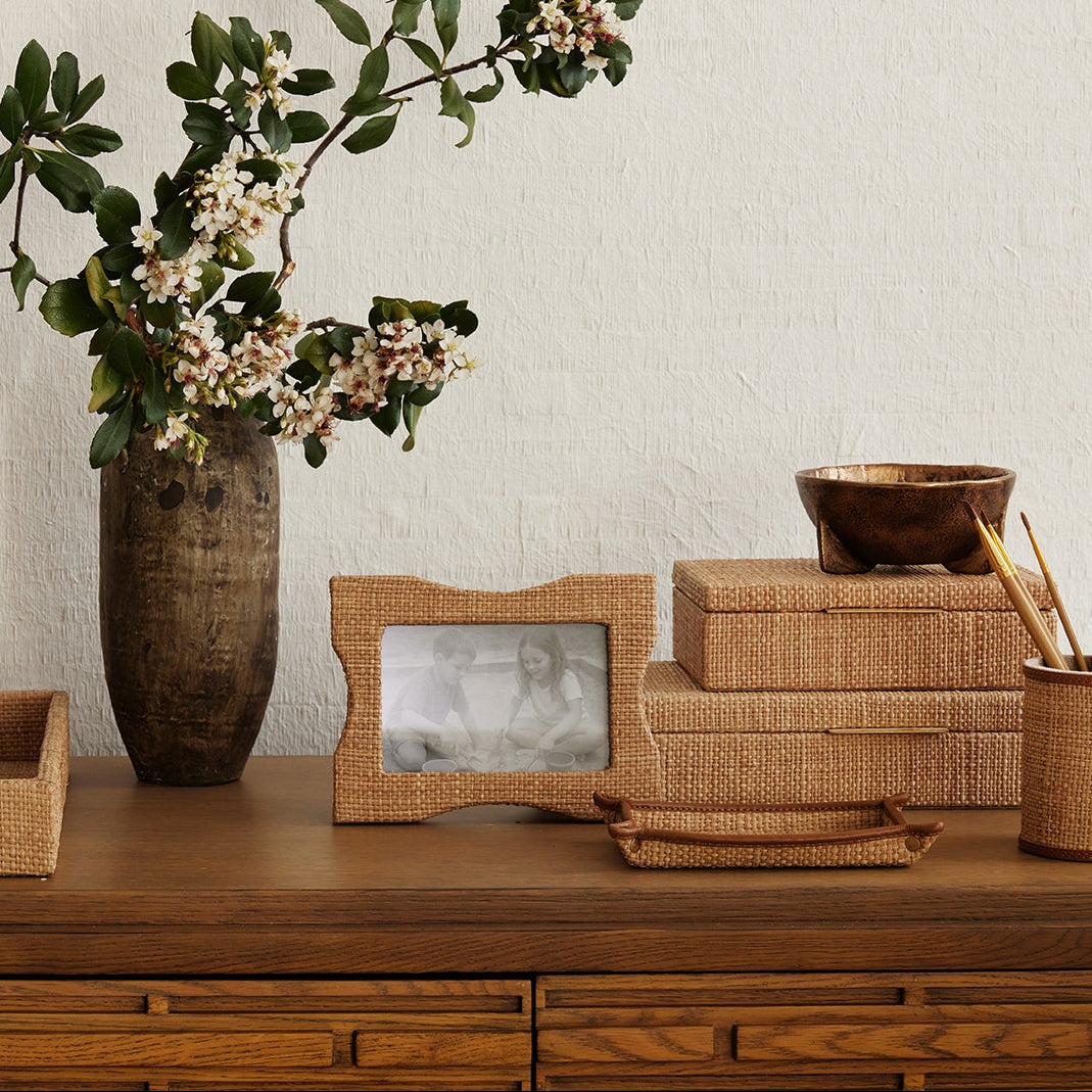 Decorative items on a wooden dresser including a vase with flowers, photo frame, and tissue box.