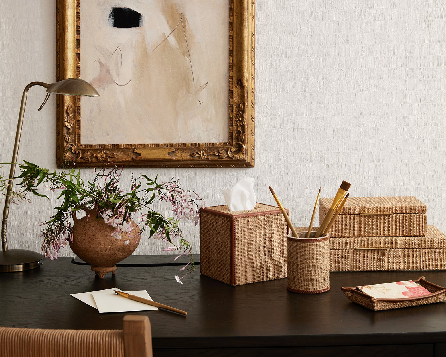 Decorative items on a wooden desk with a framed painting in the background