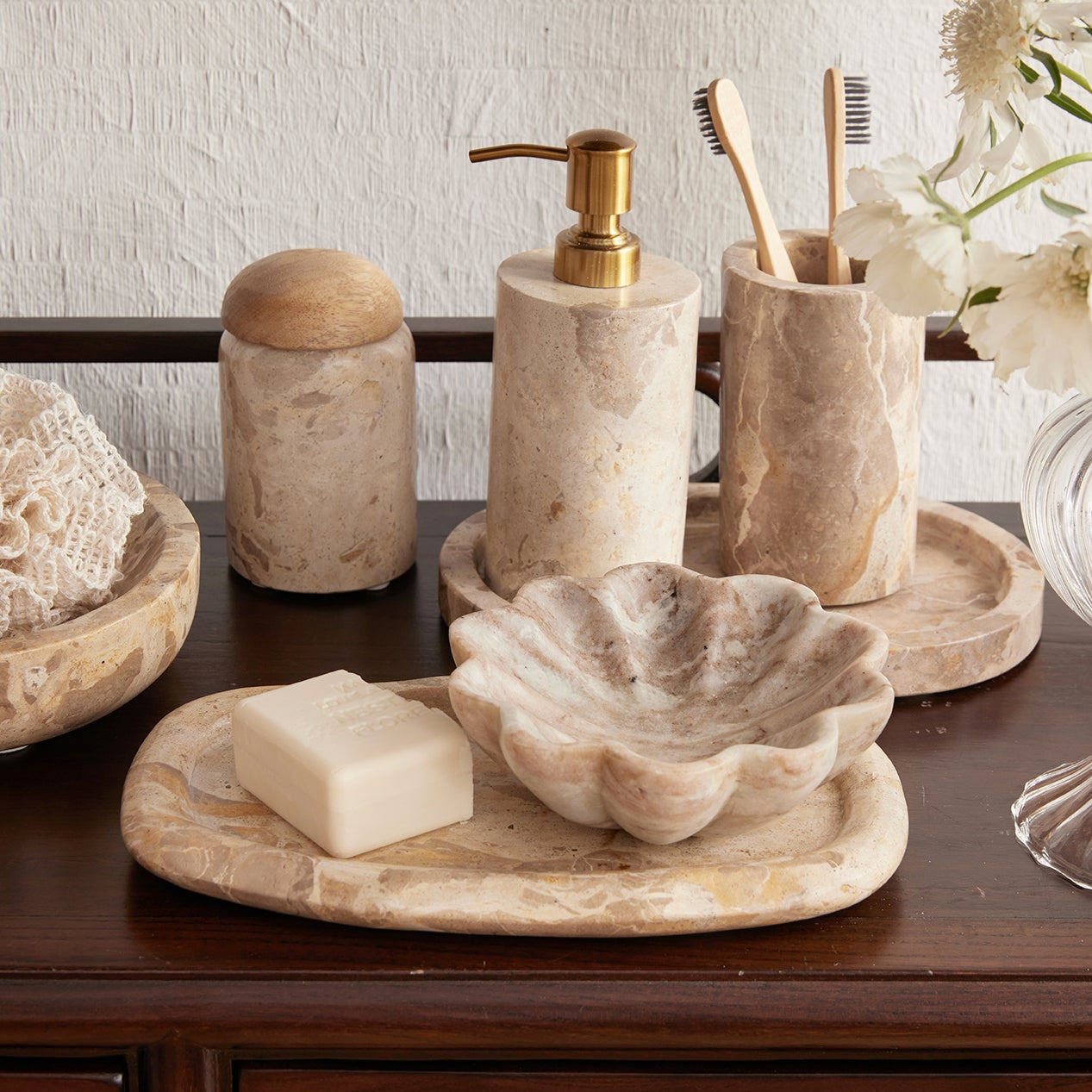 Bathroom accessories including a soap dispenser, toothbrush holder, and soap on a wooden surface.