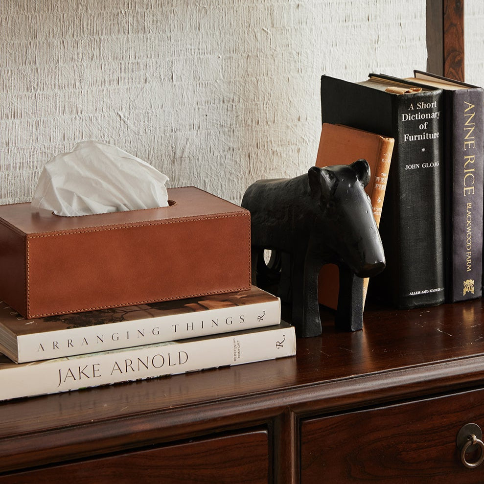 Wooden shelf with decorative items including books, a tissue box, and a black figurine.