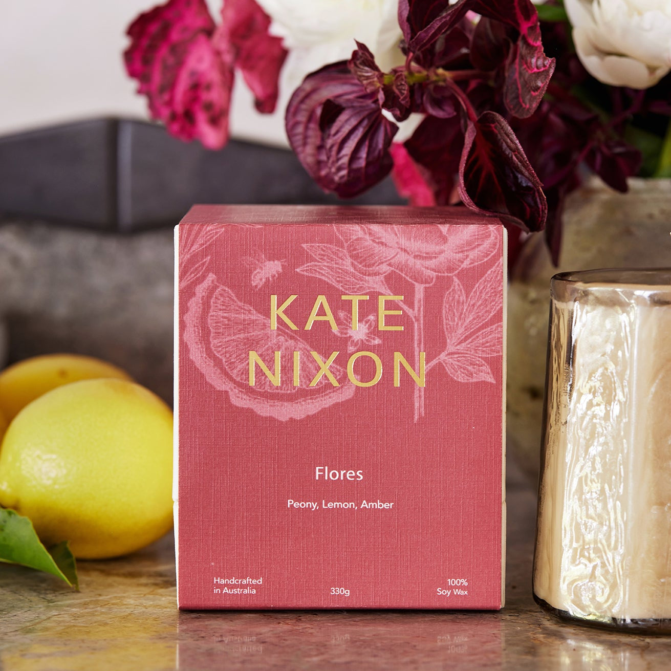 Pink box of Kate Nixon 'Flores' with flowers and lemon in the background