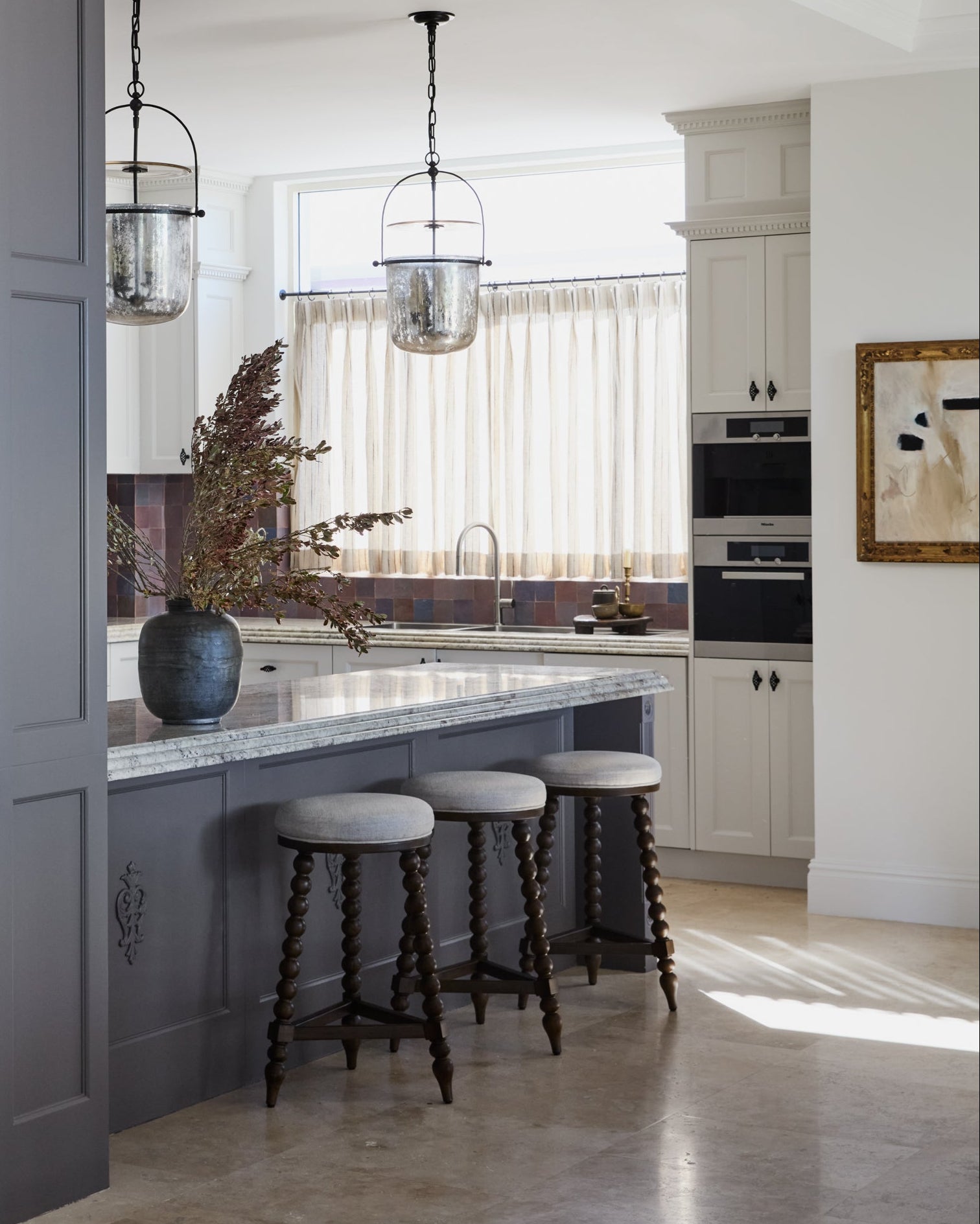 Modern kitchen with gray island, white cabinets, and decorative elements.