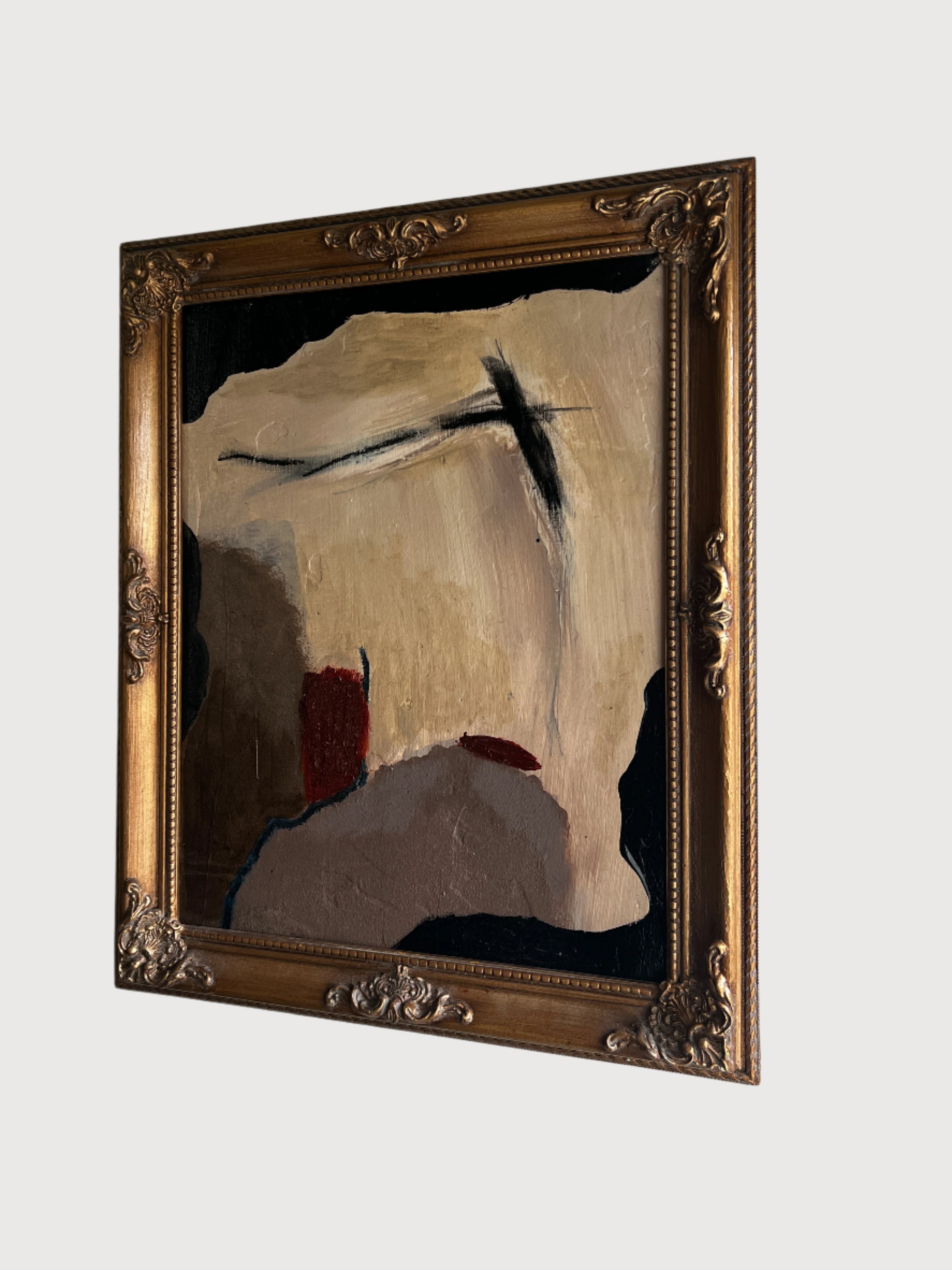 Abstract painting in a gold frame on a white wall