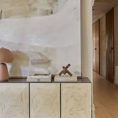 Modern interior with a wooden sideboard, abstract painting, and decorative items.