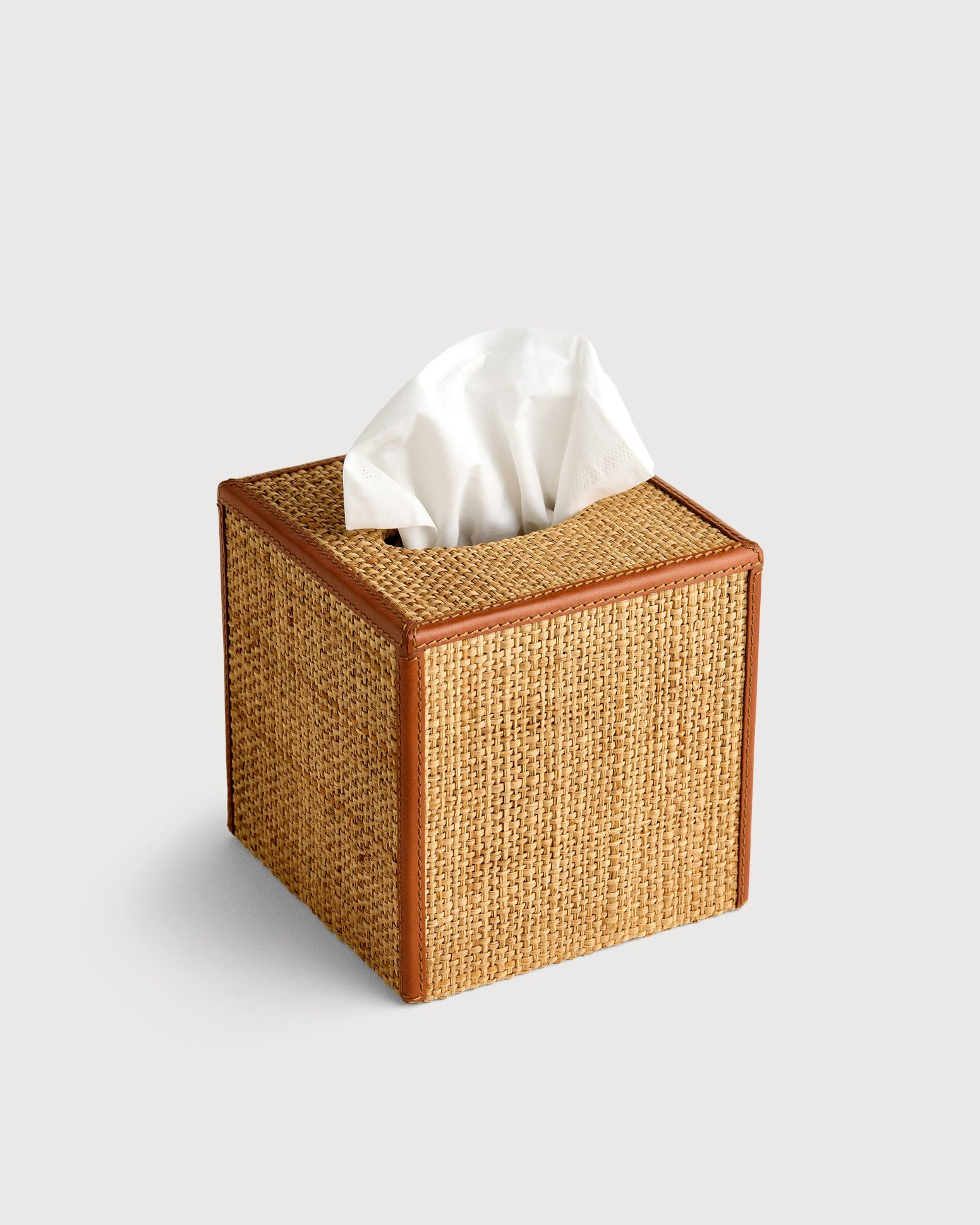 Woven tissue box cover with tissues on a light gray background