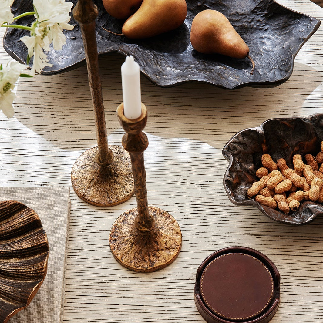 Decorative table setting with candles, bowls of snacks, and flowers on a wooden surface.