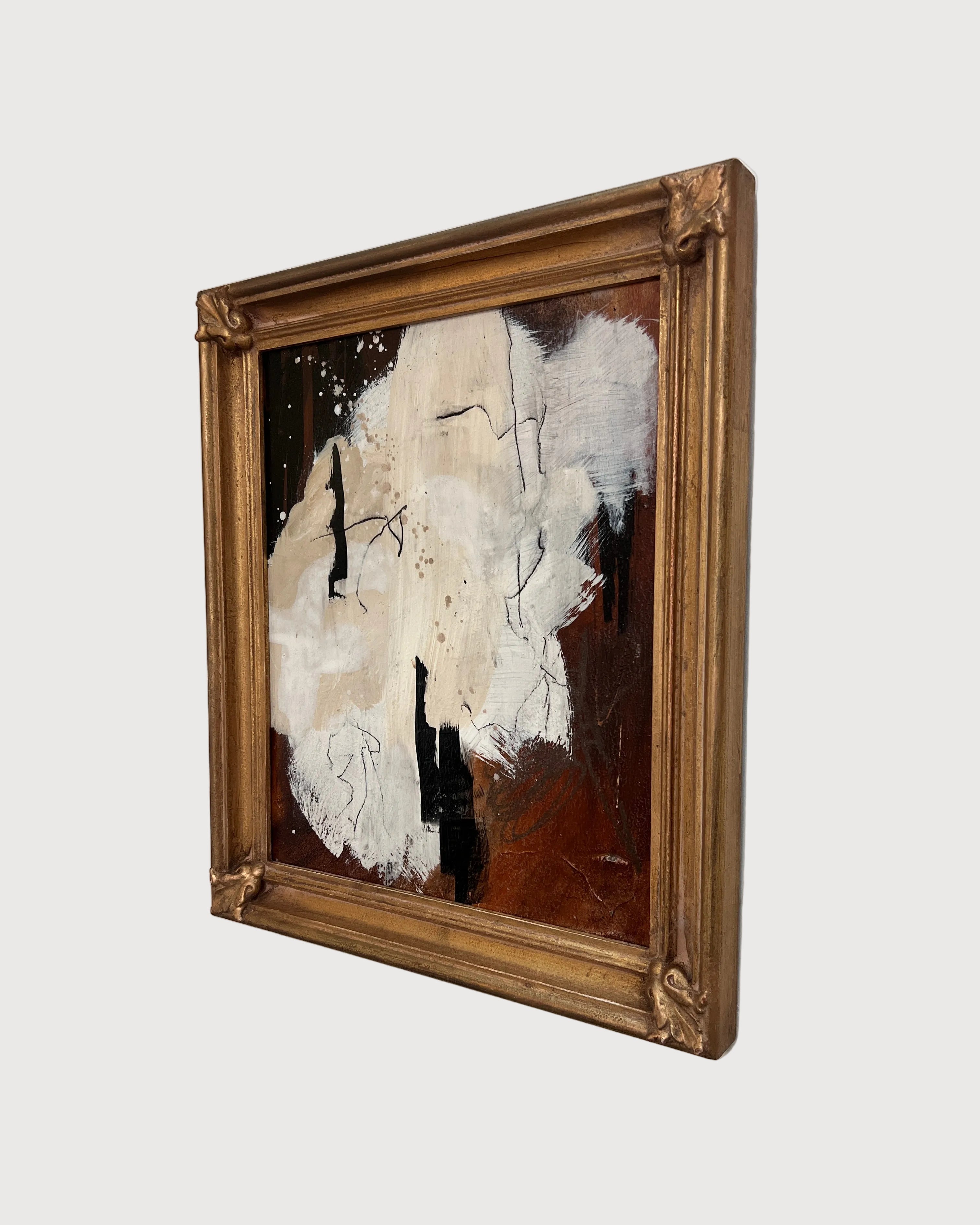 Abstract painting in a gold frame on a white wall