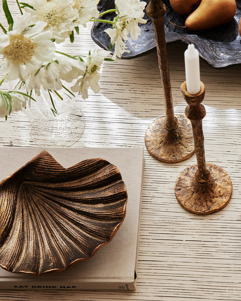 Decorative table setting with candles, bowls of snacks, and flowers on a wooden surface.