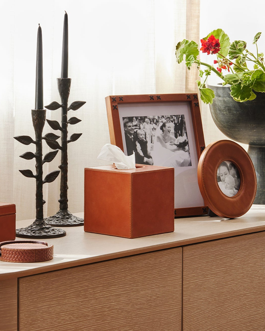 Decorative items on a wooden surface including boxes, a glass with a drink, candles, and a photo frame.