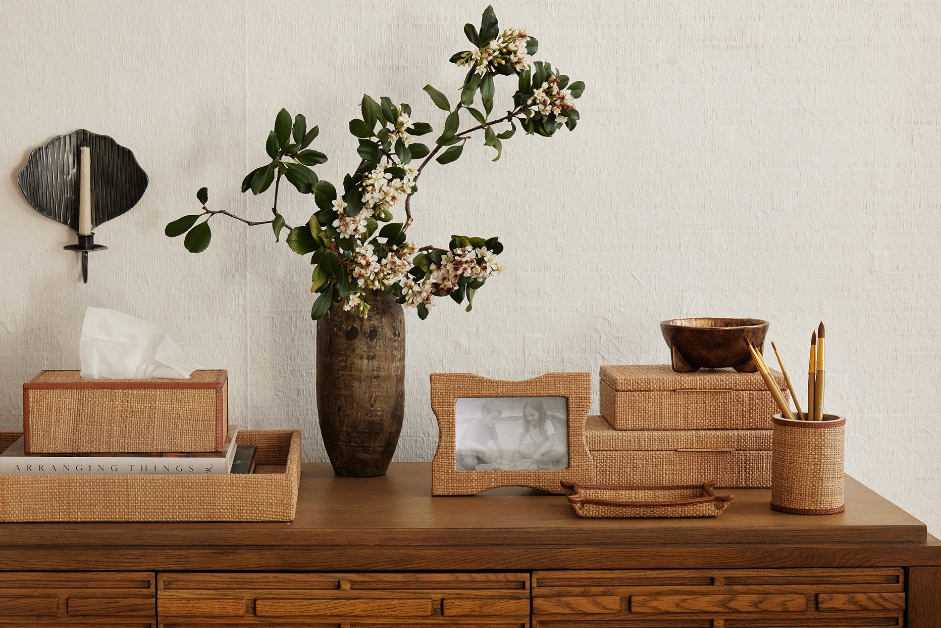 Decorative items on a wooden dresser including a vase with flowers, photo frame, and tissue box.