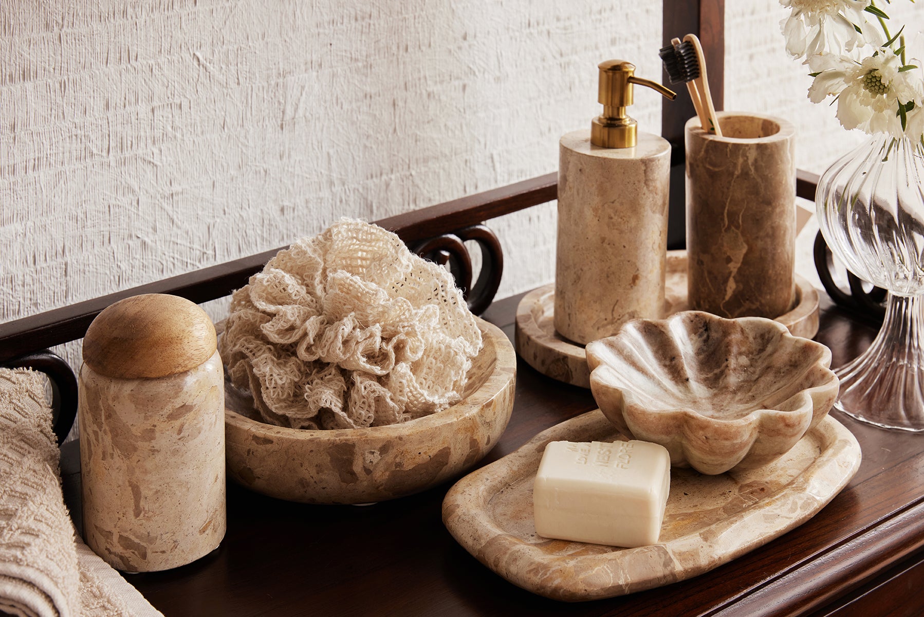Bathroom accessories including a loofah, soap, and dispenser on a wooden surface.