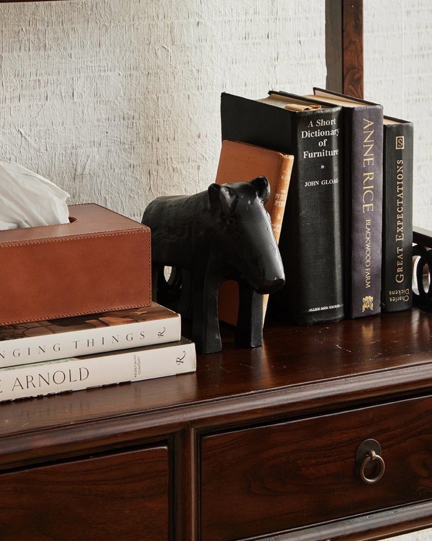 Wooden shelf with decorative items including books, a tissue box, and a black figurine.