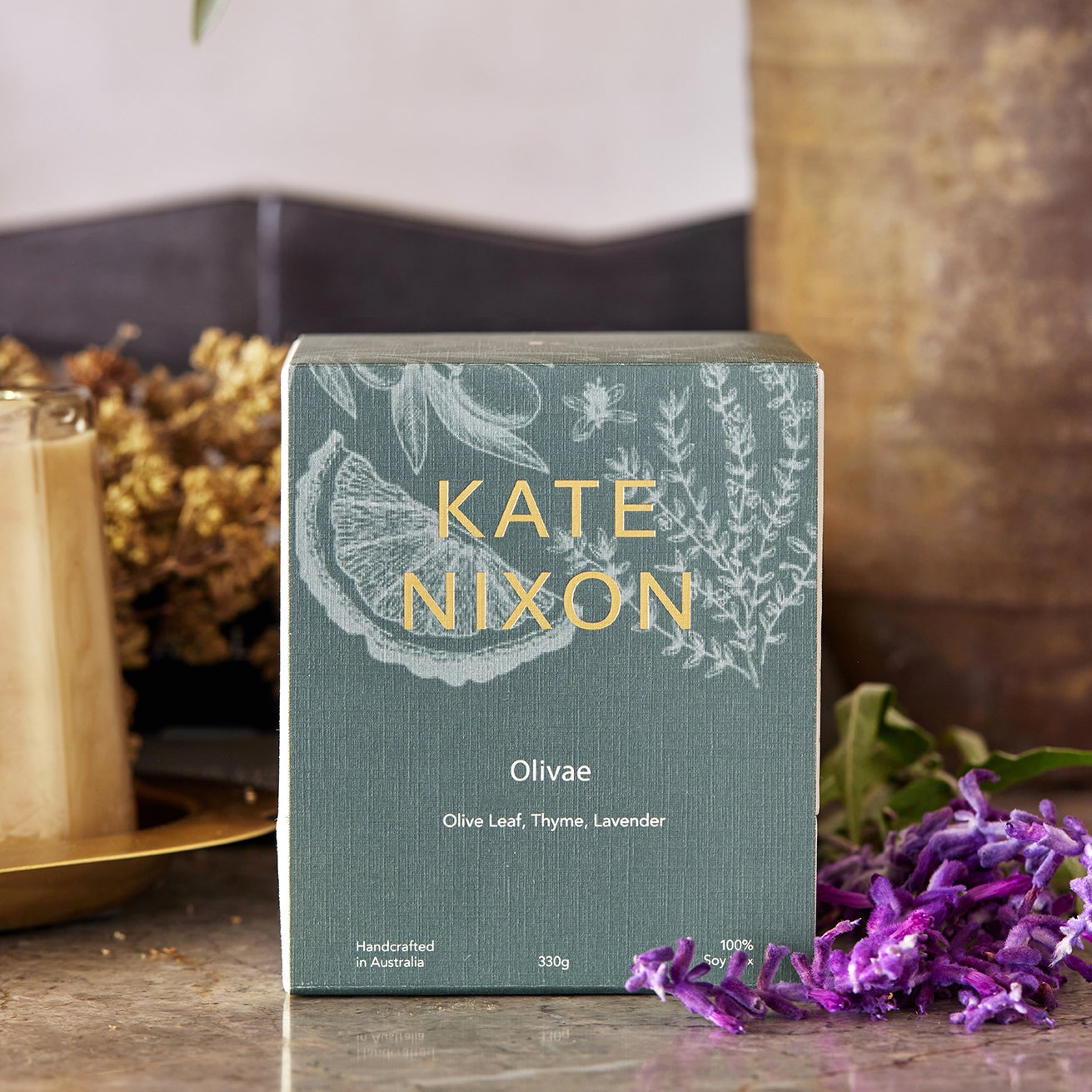 Kate Nixon OLIVAE candle packaging on a table with decorative elements