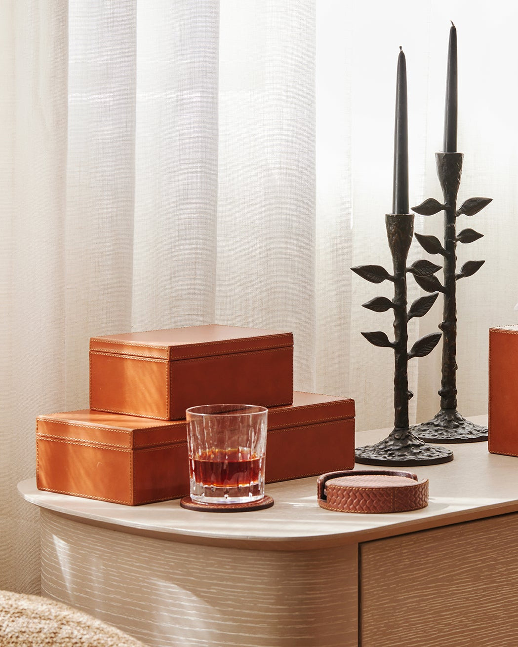 Decorative items on a wooden surface including boxes, a glass with a drink, candles, and a photo frame.