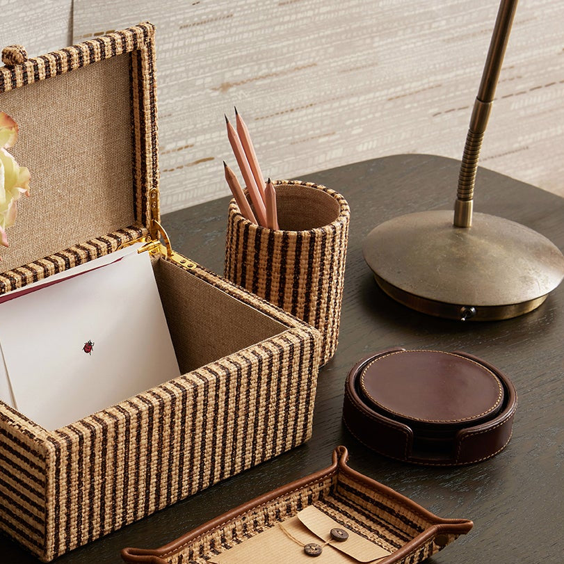 Decorative desk setup with a photo frame, tea set, and stationery items on a wooden surface.