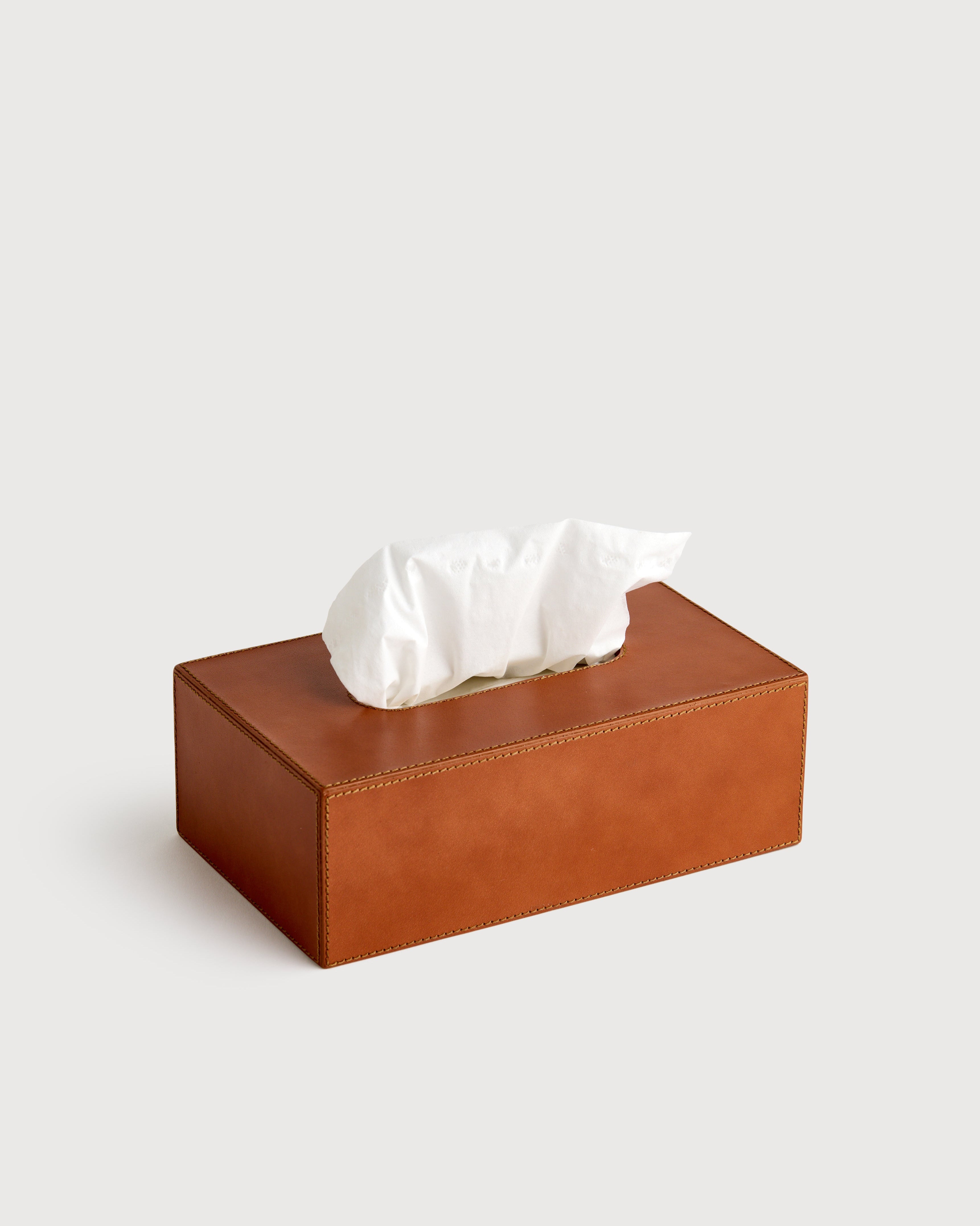 Brown leather tissue box with white tissues on a light gray background