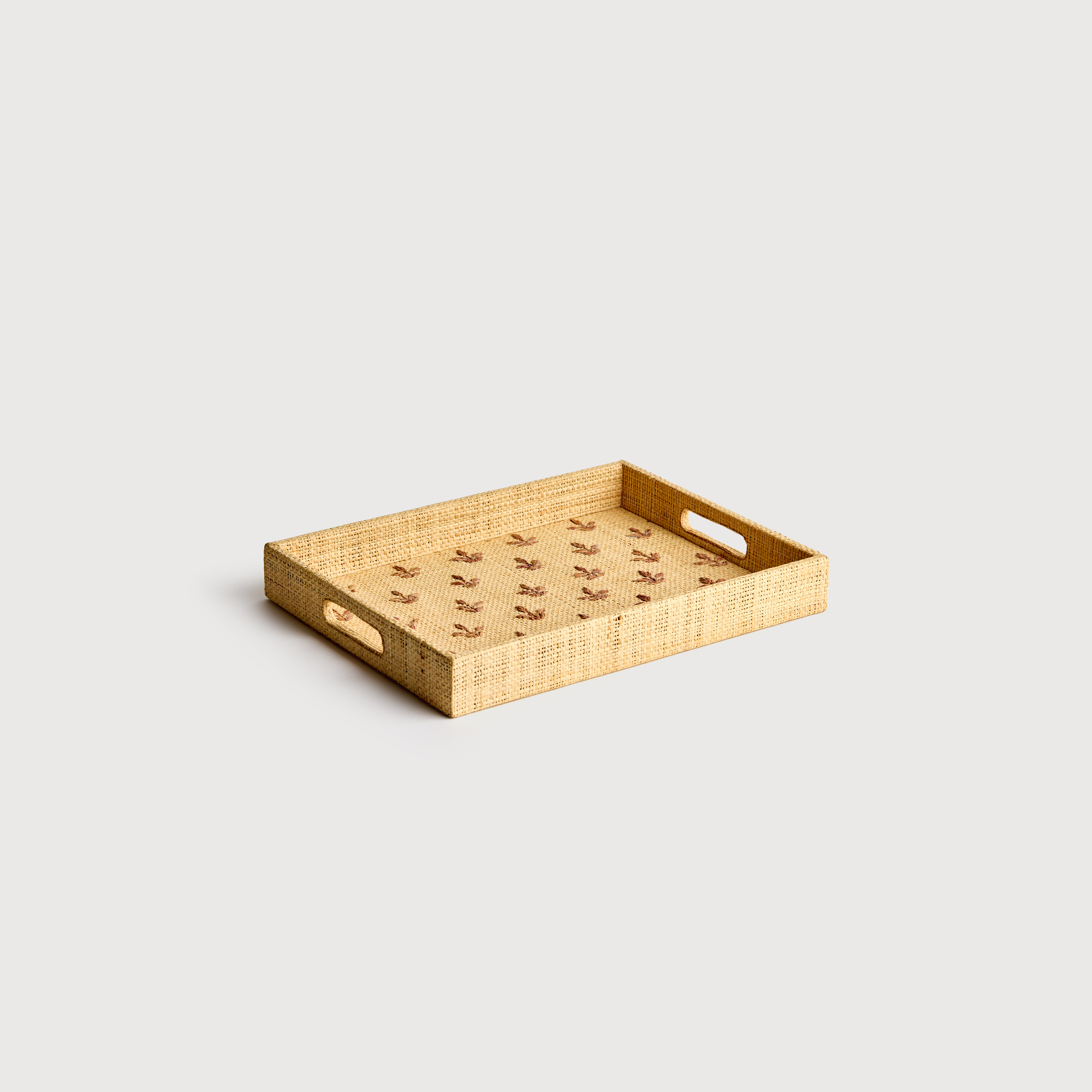 Woven rectangular tray with handles on a light gray background